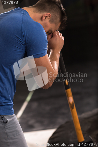 Image of man workout with hammer and tractor tire