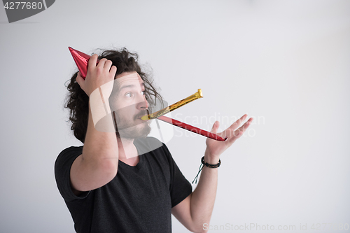 Image of Portrait of a man in party hat blowing in whistle