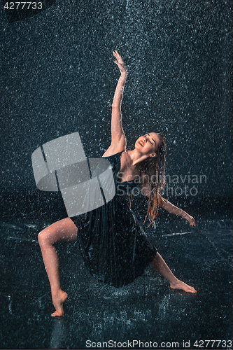 Image of The young beautiful modern dancer dancing under water drops