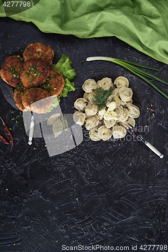 Image of Fried cutlets and russian pelmeni on black background