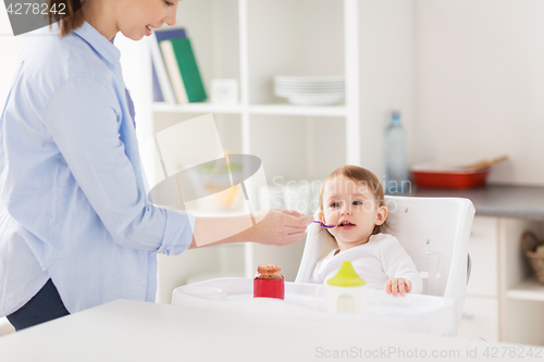 Image of happy mother feeding baby with puree at home