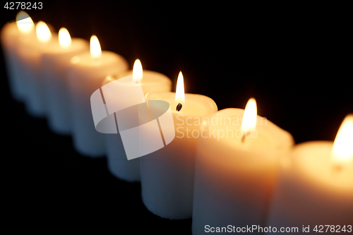 Image of candles burning in darkness over black background