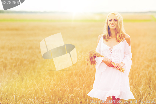 Image of happy young woman with spikelets on cereal field