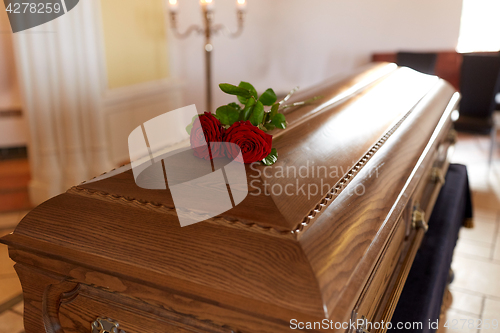 Image of red rose flowers on wooden coffin in church