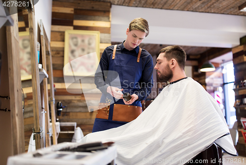 Image of barber showing hair styling wax to male customer