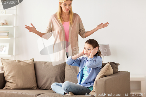 Image of girl closing ears to not hear angry mother at home