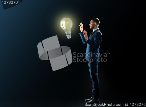 Image of businessman with lightbulb over black background