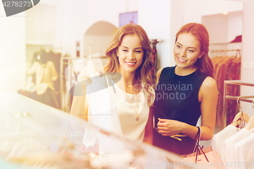 Image of happy women with shopping bags at clothing shop