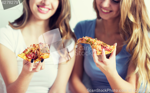 Image of happy friends or teen girls eating pizza at home