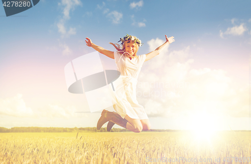 Image of happy woman in wreath jumping on cereal field