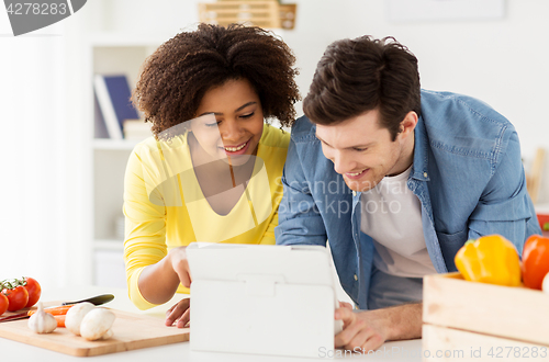 Image of happy couple with tablet pc cooking food at home