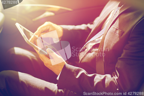 Image of senior businessman with tablet pc driving in car