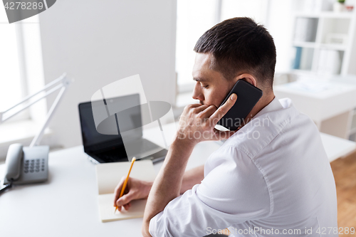 Image of businessman calling on smartphone at office