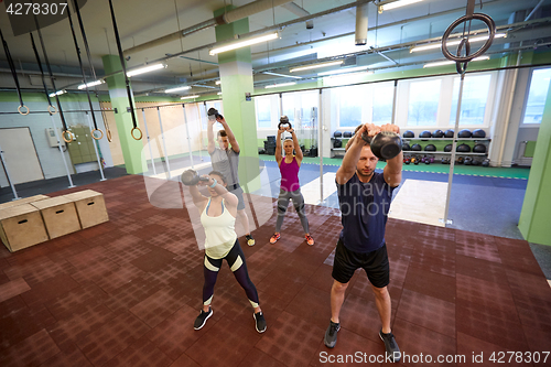 Image of group of people with kettlebells exercising in gym