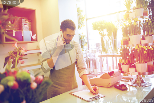 Image of man with smartphone making notes at flower shop