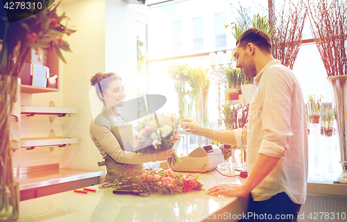 Image of smiling florist woman and man at flower shop