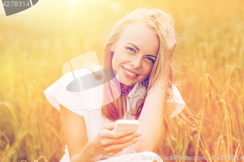 Image of happy young woman with smartphone on cereal field