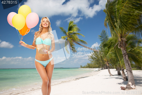 Image of happy woman in bikini with air balloons on beach