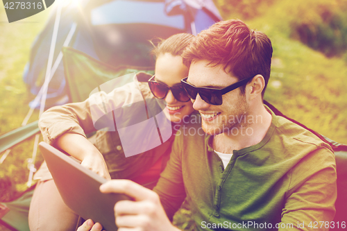 Image of happy couple with tablet pc at camping tent