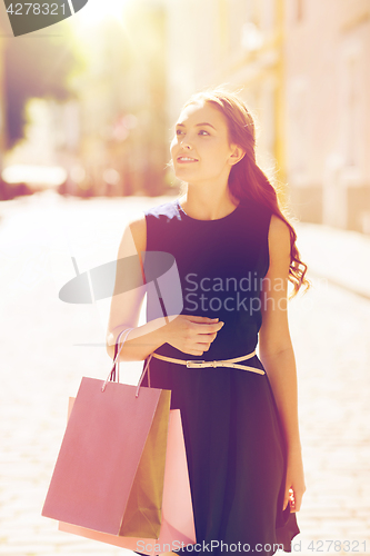 Image of happy woman with shopping bags walking in city 