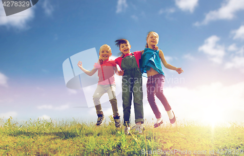 Image of group of happy kids jumping high on green field