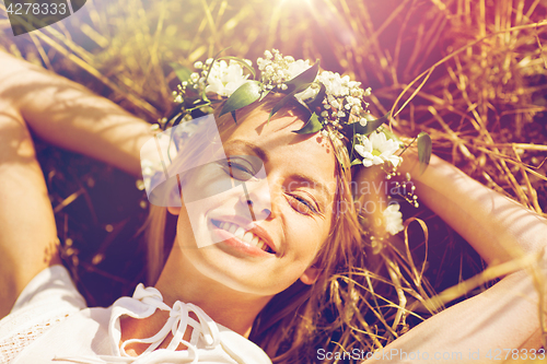 Image of happy woman in wreath of flowers lying on straw