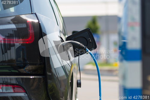 Image of Power supply plugged into an electric car being charged.