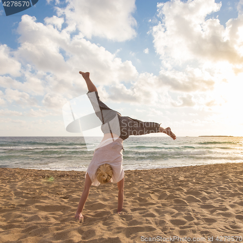 Image of Free Happy Woman Turning Cartwheel Enjoying Sunset on Sandy Beach.