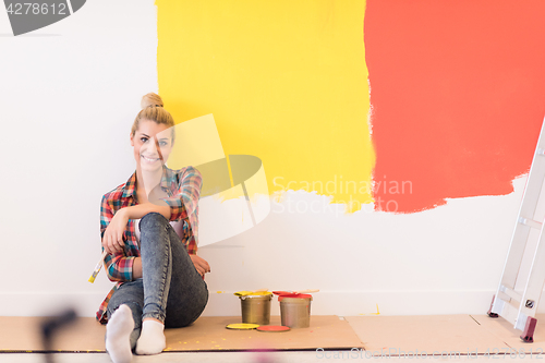 Image of young female painter sitting on floor