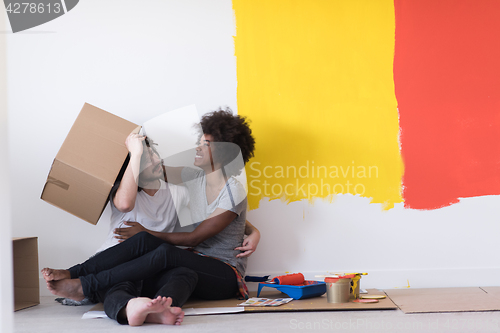 Image of young multiethnic couple playing with cardboard boxes