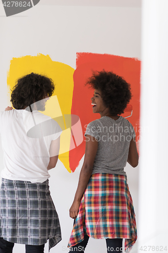 Image of multiethnic couple painting interior wall