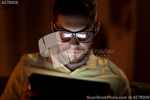 Image of young man with tablet pc networking at night