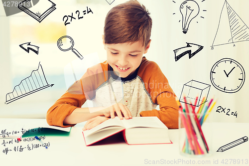 Image of smiling, student boy reading book at home