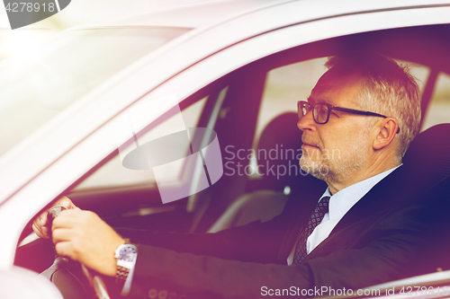 Image of happy senior businessman driving car