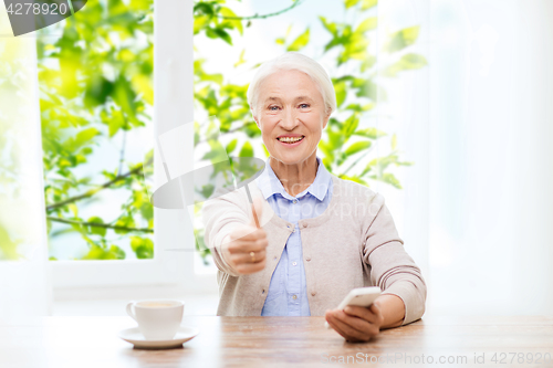 Image of senior woman with smartphone showing thumbs up