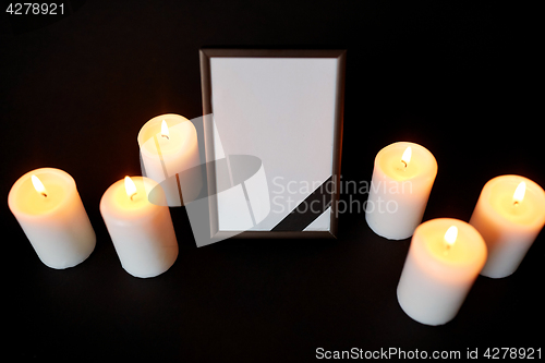 Image of photo frame with black mourning ribbon and candles