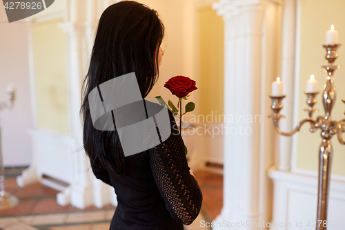 Image of sad woman with red rose at funeral in church