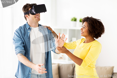 Image of happy couple with virtual reality headset at home