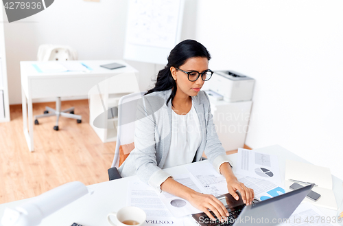 Image of businesswoman with laptop working at office