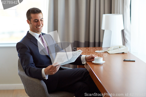 Image of businessman reading newspaper and drinking coffee