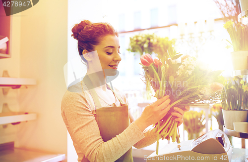 Image of smiling florist woman making bunch at flower shop