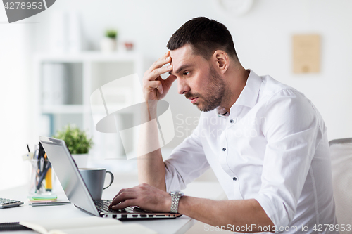 Image of stressed businessman with laptop at office