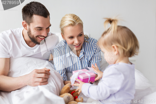 Image of happy family with gift box in bed at home