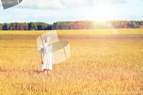 Image of happy young woman in flower wreath on cereal field