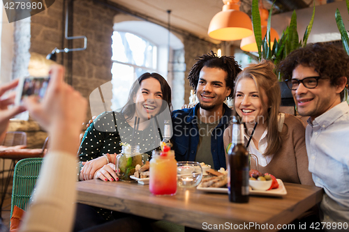 Image of friends with smartphone photographing at cafe