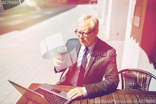 Image of senior businessman with laptop drinking coffee