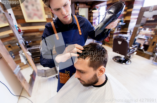 Image of barber with fan drying male hair at barbershop