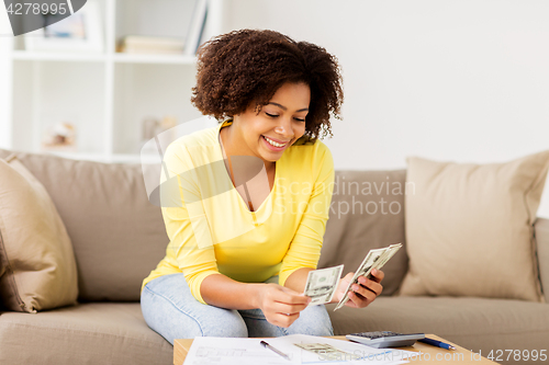 Image of african woman with papers and calculator at home