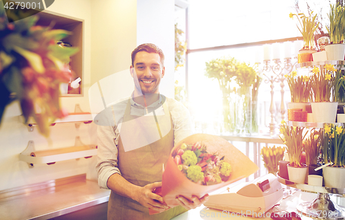 Image of smiling florist man making bunch at flower shop