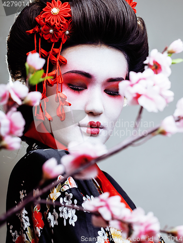 Image of young pretty geisha in kimono with sakura and red decoration design on white background